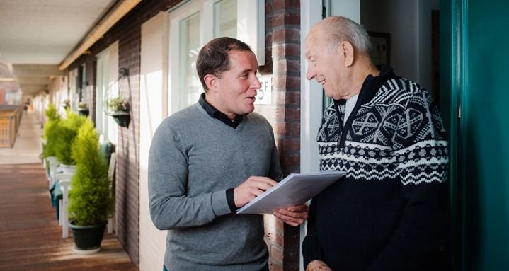 Bewonersconsulent Woonzorg Nederland aan de deur in gesprek met huurder