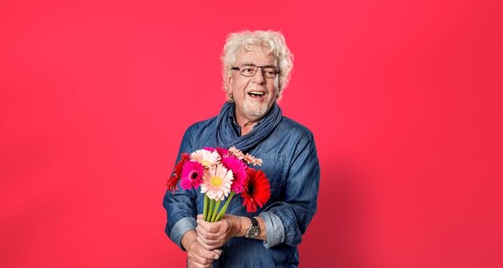 Man 60+ houdt bos bloemen vast