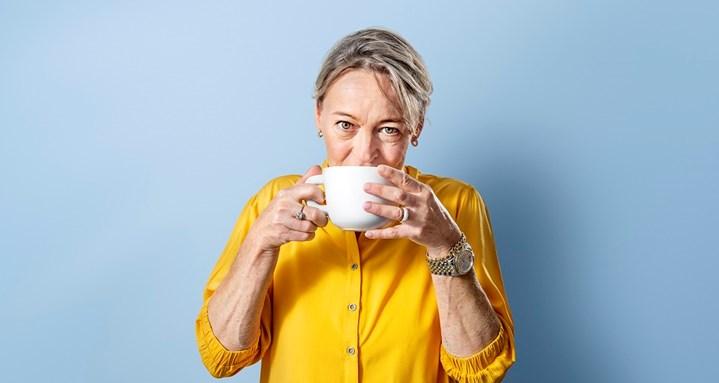 Blije vrouw drinkt kop koffie