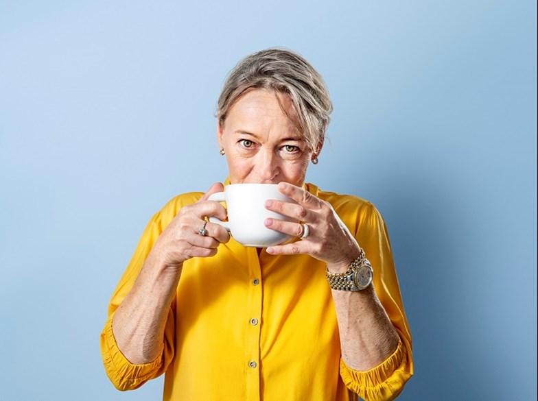 Blije vrouw drinkt kop koffie